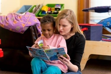 Kelsey Randel reads with a friend at New Directions Shelter. 