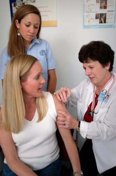 A nurse administers a dTap vaccination to a woman